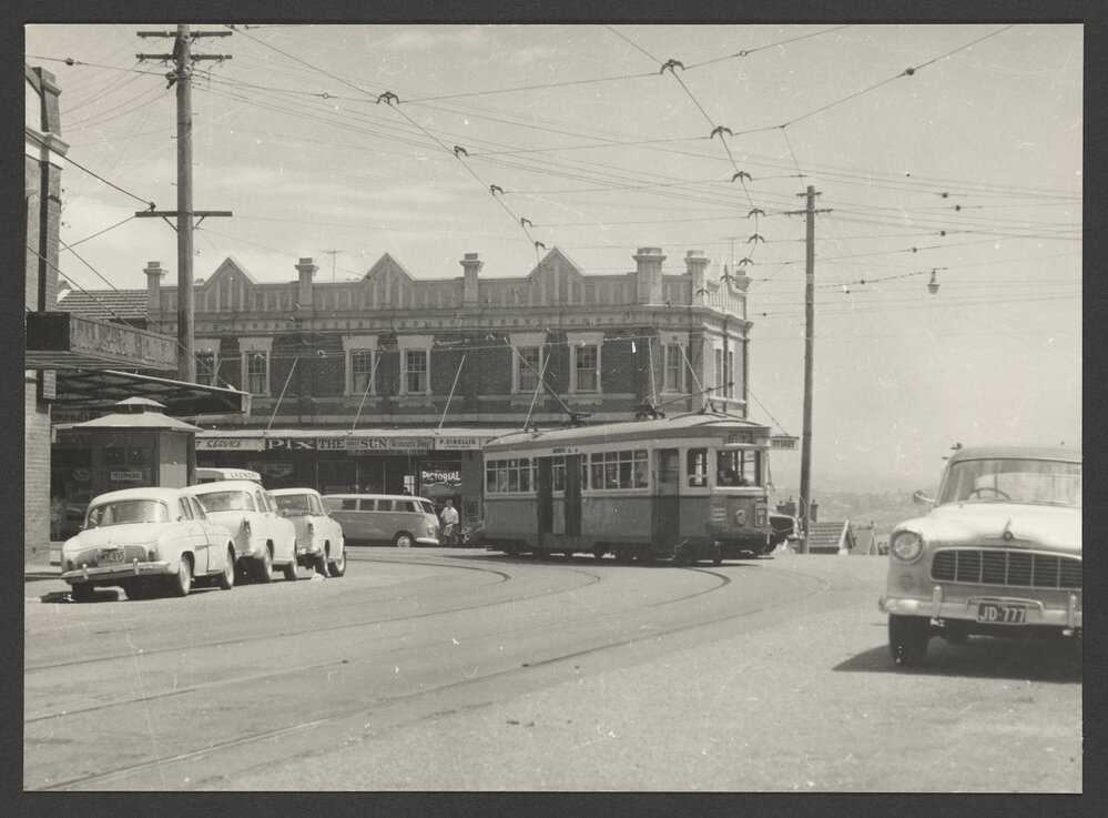 R Class Tram turning from Bondi Road into Denham Street, Bondi. Background commercial &amp; residental buildings 298 - 300 Bondi Road. Federation architecture.
