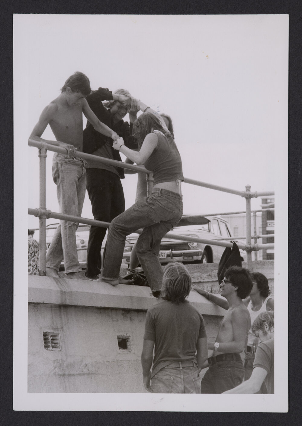 Bathers, young woman climbing promenade wall, Bondi beach.