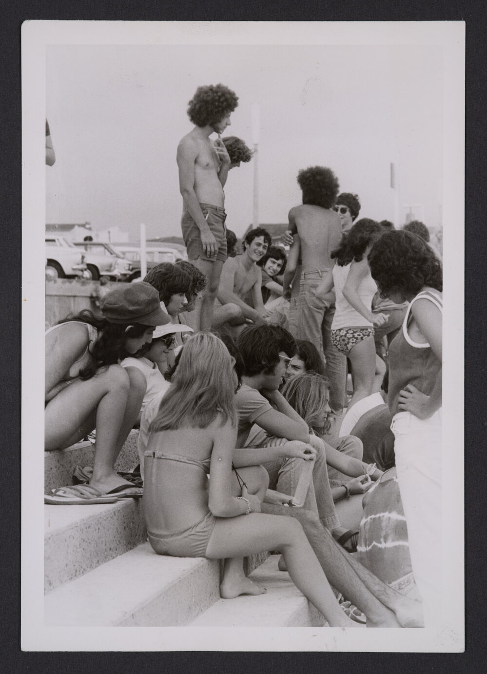 Bathers, young people sitting on steps to Promenade at Bondi beach.