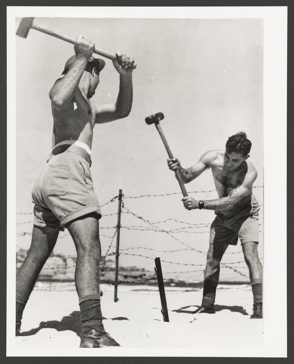 Bondi beach, two soldiers installing barbed wire on Bondi beach during World War II.