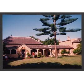 Western ( front ) of house and two - storey extension. Norfolk island pine tree.