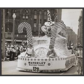 Waverley Muncipal Council float in Waratah Procession, George St, Sydney. Seated right on float is Lynette Whillier who modelled for one of the "Bondi Mermaids".