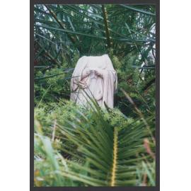 Headless female figure amoungst palms