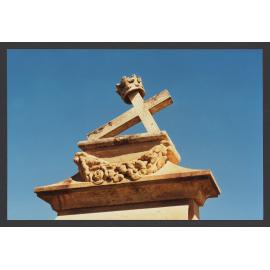 Crown and leaning cross on pedestal in sandstone