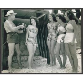 Beach girls and Stan McDonald Bondi beach : Stan McDonald with spray gun and from left to right: Monica Kelly, Judith ( Judy ) Parnell, Patty Jupp, Norma Weston.  Girls aged approx. 16 years old.