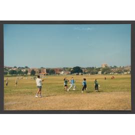 Peter Tos, coach of Bondi Radiers Gridiron club, plays flag gridiron with children in Queens Park.